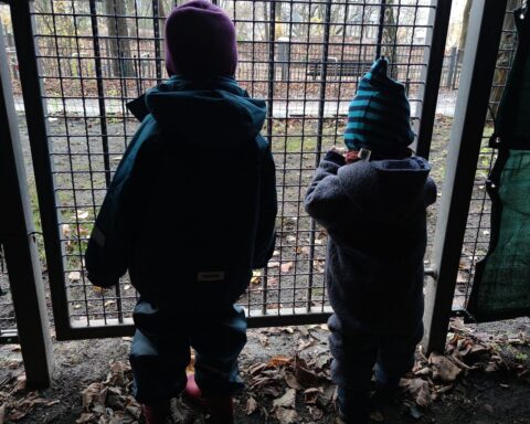 Kinder hinter einem Gitter symbolisieren die Probleme der Kinderarmut und gesellschaftlicher Ausgrenzung.