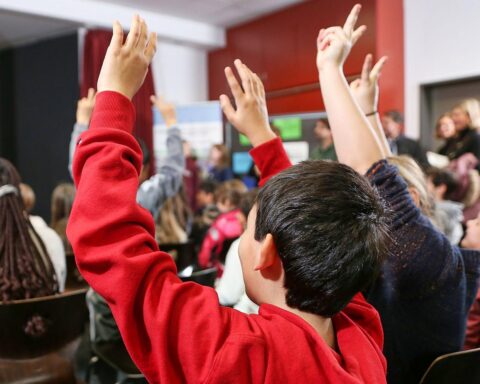 Kinder in einem Klassenzimmer, Lehrer erklärt; Fokus auf Bildung und gemeinsame Schulstruktur.