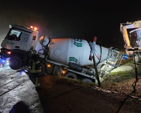 Betonmischer im Graben blockiert Bahnstrecke, Feuerwehr beleuchtet Unfallstelle, Zugverkehr eingestellt.