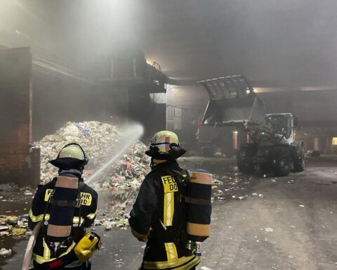 Feuerwehr löscht Brand in Lagerhalle, dichte Rauchentwicklung und Einsatzkräfte sichtbar.