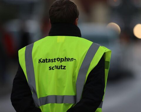 Ein DRK-Logo mit Helfern, Erste-Hilfe-Ausrüstung und Vorräten für den Katastrophenschutz.