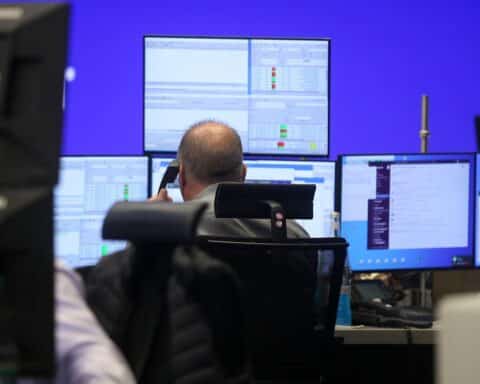 Frankfurter Börse mit Dax-Index, Anleger am Monitor, wechselhafte Märkte, Euro und Dollar-Kurs.