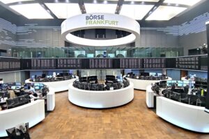 Dax-Logo und Frankfurter Börse mit steigenden Kursen, Analysten beobachten Marktreaktionen.