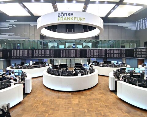 Dax-Logo und Frankfurter Börse mit steigenden Kursen, Analysten beobachten Marktreaktionen.