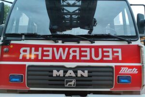 Feuerwehr im Einsatz bei Wohnhausbrand, betroffene Bewohner evakuiert, Vermisster wird gesucht.