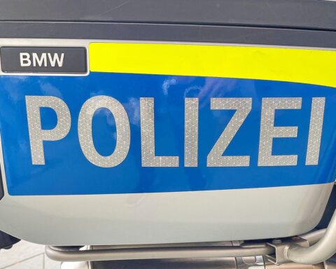 Ein Polizeiwagen vor einem Wohnhaus, umgeben von Einsatzkräften, nach einer tragischen Tat.