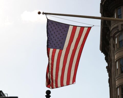 US-Flagge vor spektakulärer Landschaft, symbolisiert Alaska nach Erdbeben der Stärke 6,1.