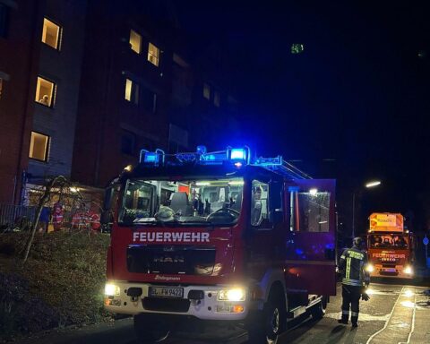 Einsatzkräfte der Feuerwehr löschen Brand in Mehrfamilienhaus, schützen und retten Personen aus Gefahr.