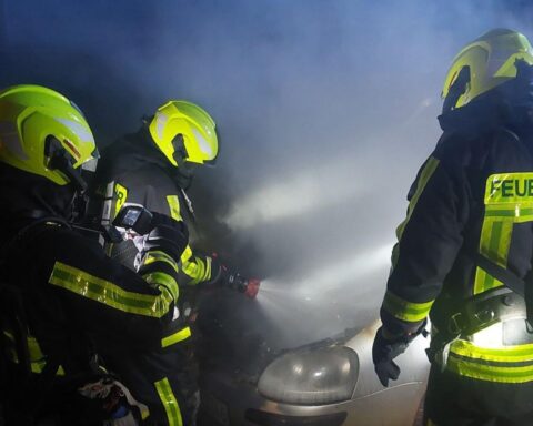 Feuerwehr löscht brennende Pkw; Einsatzkräfte kämpfen gegen Flammen in der Nacht.
