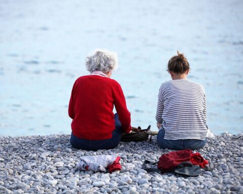 Alte und junge Frauen am Strand symbolisieren den generationsübergreifenden Dialog zur Rentenpolitik.