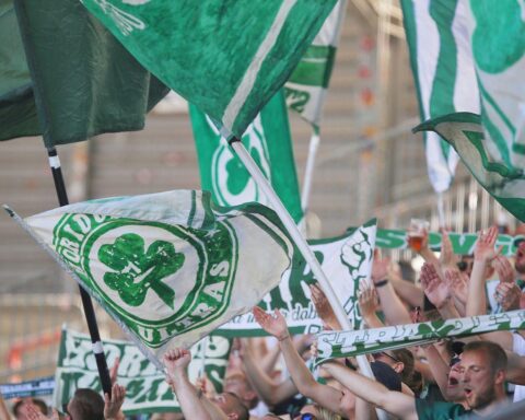 Fans jubelnd im Stadion, symbolisieren die Leidenschaft und Herausforderungen des Vereins Greuther Fürth.