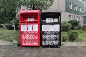 Sammelcontainer für Altkleider vor kommunalen Hintergrund, Symbol für Recycling und nachhaltige Strategien.