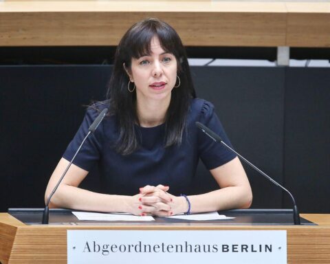 Elif Eralp auf Parteitag, umgeben von Unterstützern, Fokus auf Wohnungs- und Mietenpolitik.