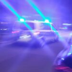 Polizeiauto sichert Unfallstelle auf Bundesstraße, beschädigtes Fahrzeug wegen umherliegendem Blechteil.