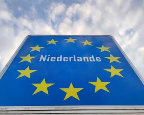 Landesschild der Niederlande vor einem diplomatischen Hintergrund, symbolisiert Entspannung im Nexperia-Konflikt.