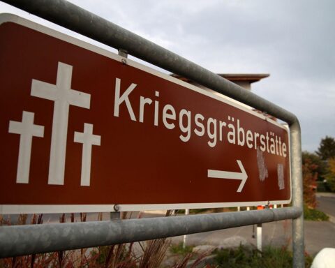 Kriegsgräberstätte mit übergrown Vegetation, Symbol der Vernachlässigung und finanziellen Herausforderungen der Fürsorge.