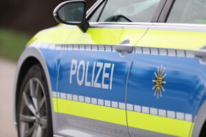 Polizeiauto vor einer Bushaltestelle, umgeben von Einsatzkräften und Hinweisen zum Vorfall.
