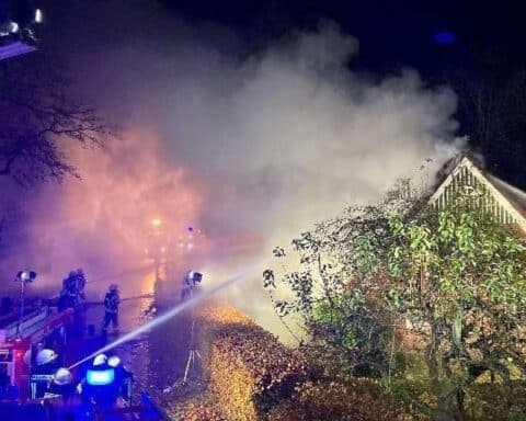 Ein abgebranntes Reetdachhaus in Kehdingbruch, Feuerwehrleute löschen die verbliebenen Flammen.