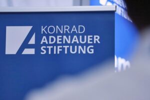 Konferenzraum mit Beamten und Politikern diskutiert Reformen der Bundesverwaltung. Dokumente und Laptops sichtbar.