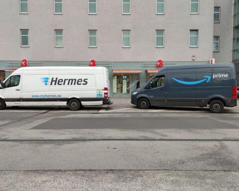 Transporter von Hermes und Amazon Prime vor einem Hintergrund von Arbeitsschutz-Debatten.