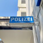 Ein Waschbär liegt leblos, verletzt durch einen Armbrustpfeil, am Ufer eines Baches.