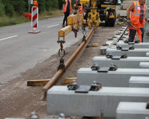 Bauarbeiter renovieren Bahnstrecke, symbolisieren notwendige Investitionen in die Verkehrsinfrastruktur der Zukunft.