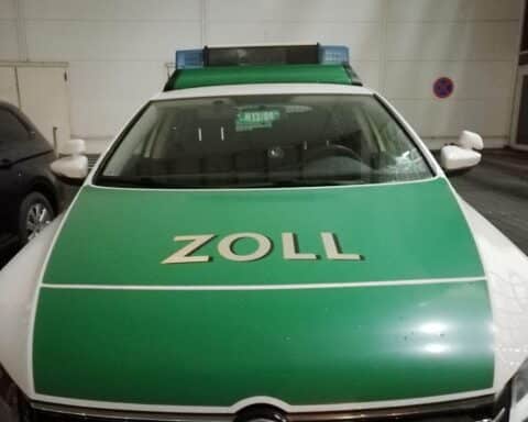 Zollbeamte bei Durchsuchung, beschlagnahmte Waren, Verdächtiger in Haft, Euro-Symbole im Hintergrund.