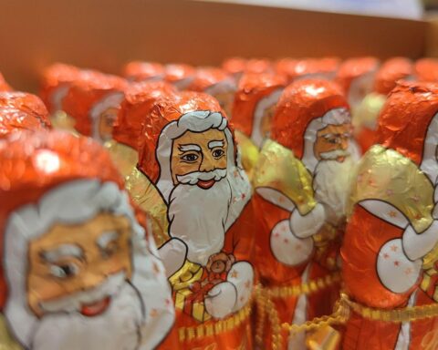 Weihnachtsmänner vor süßen Leckereien, Symbol für gestiegene Preise in der Adventszeit.