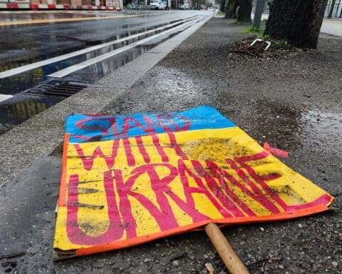 Schild "Stand with Ukraine" auf dem Boden, repräsentiert Widerstand gegen US-Friedensplan.