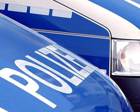 Polizeistreife vor einem Firmengebäude mit Glasbruch, Symbolbild für Ermittlungen nach Schussattacke.