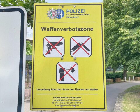 Symbolische Darstellung einer Waffenverbotszone mit Verbotsschildern und abgestellten Waffen.
