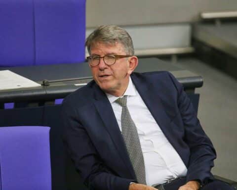 Wolfram Weimer in offizieller Kleidung, vor einem Hintergrund, der politische Autorität symbolisiert.