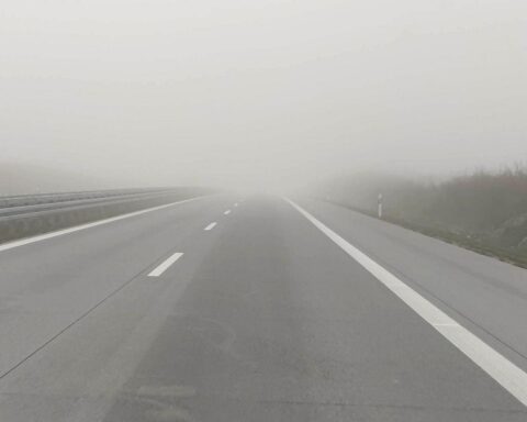 Nebel auf einer Autobahn, grauer Himmel, leichtes Regenwetter, herbstliche Landschaft in Bayern.