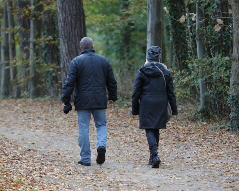 Paar spaziert bei wechselhaftem Wetter mit Sonne, Wolken und ersten Niederschlägen.