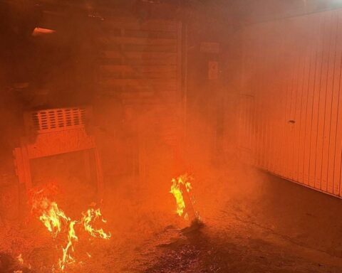 Einfamilienhaus mit brennendem Anbau, Feuerwehr im Einsatz, Rauch und Flammen sichtbar.