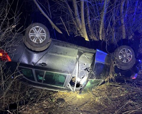 Abgeschlepptes Auto nach Unfall, Fahrer verletzt, Wagen auf Dach im Gebüsch.