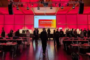 Delegierte sitzen an Tischen, diskutieren wichtige Entscheidungen beim BSW-Parteitag in Magdeburg.