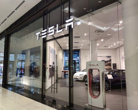 Tesla-Shop im Hintergrund; kritische Aussage des Erzbischofs Heiner Koch über hohe Managergehälter.