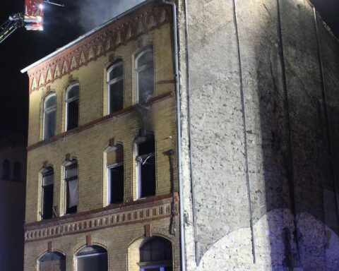 Brand eines Mehrfamilienhauses mit Feuerwehr und Polizei im Einsatz, Bewohner in Sicherheit.