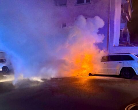 Zwei brennende PKW vor Wohngebäude, Feuerwehr löscht, starke Rauchentwicklung, keine Verletzten.