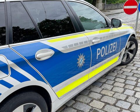 Ein Polizeiauto vor beschädigten Fahrzeugen, symbolisiert Ermittlungen zu Sachbeschädigung in Nürnberg.