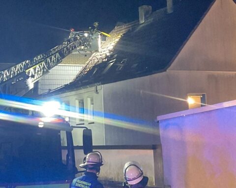 Drehleiter der Feuerwehr entfernt Teile des Daches nach Dachstuhlbrand in Dortmund.