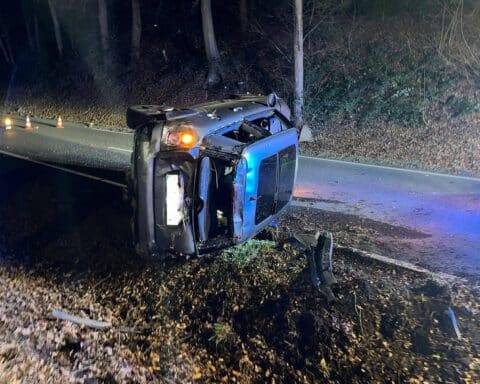 Unfallstelle mit beschädigtem Auto, Polizei und Rettungsdienst im Einsatz. Verletzte Personen werden versorgt.