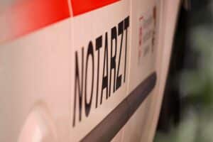 Ein Rettungswagen assistiert nach einem Verkehrsunfall mit beschädigten Fahrzeugen und verletzten Personen.