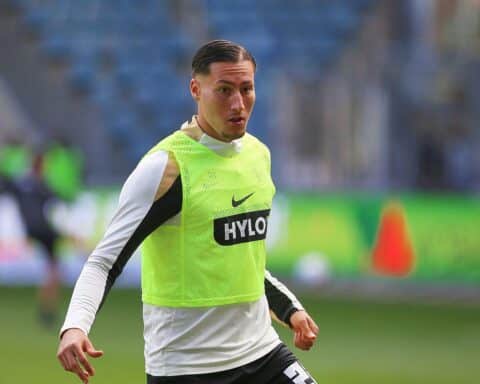Younes Ebnoutalib mit Fußball im Stadion, Eintracht Frankfurt-Logo im Hintergrund, feierliche Stimmung.