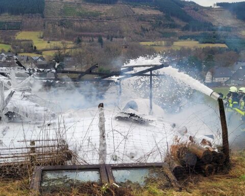 Scheune in Flammen, Feuerwehr im Einsatz, Einsatzkräfte löschen Brand mit Schaum und Bagger.