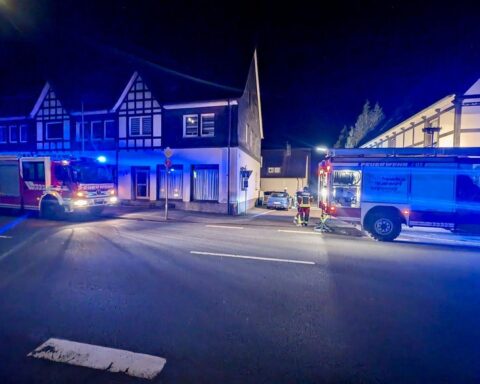 Feuerwehrlöscharbeiten in einem Mehrfamilienhaus mit Rauch und Einsatzkräften im Einsatz.