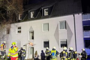 Feuerwehr rettet Bewohner aus brennender Dachgeschosswohnung, Flammen und Rauch sichtbar.
