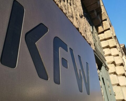 KfW-Büro mit Mitarbeitern, die an einem Tisch arbeiten und digitale Anreize genießen.