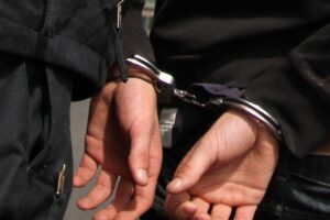 Polizisten verhaften einen Mann in Handschellen, Geldstrafe und Drogen im Gepäck entdeckt.